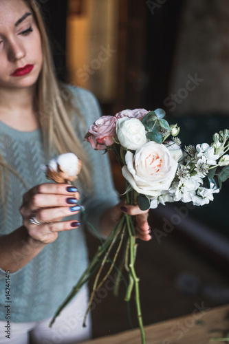 Florist at work: pretty young blond woman holds fashion modern bouquet of different flowersv photo