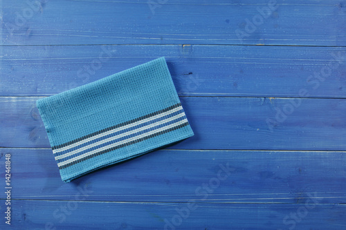 Wooden picnic table with blue dishcloth on photo