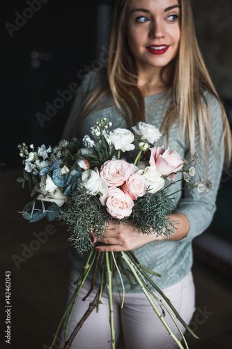 Florist at work: pretty young blond woman holds fashion modern bouquet of different flowersv photo