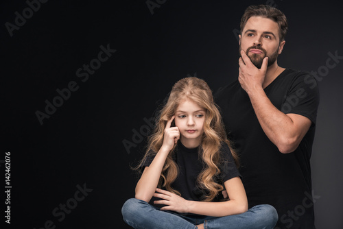 adorable pensive daughter and pensive father on black with copy space