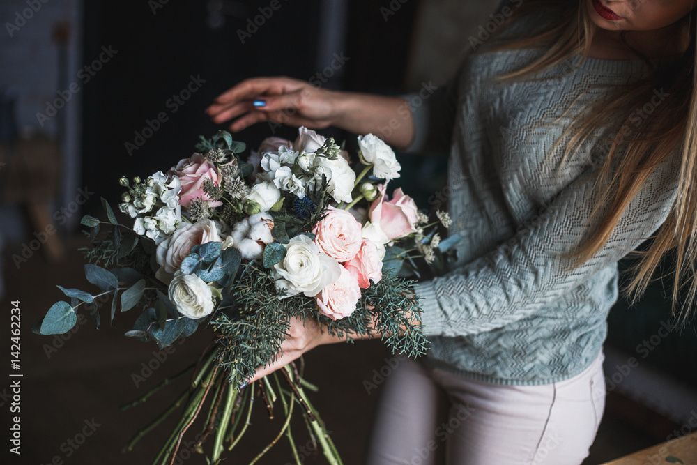 Florist at work: pretty young blond woman holds fashion modern bouquet of different flowersv Florist at work: pretty young blond woman holds fashion modern bouquet of different flowersv