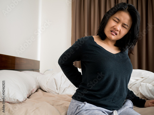 woman suffering from back pain sitting on bed