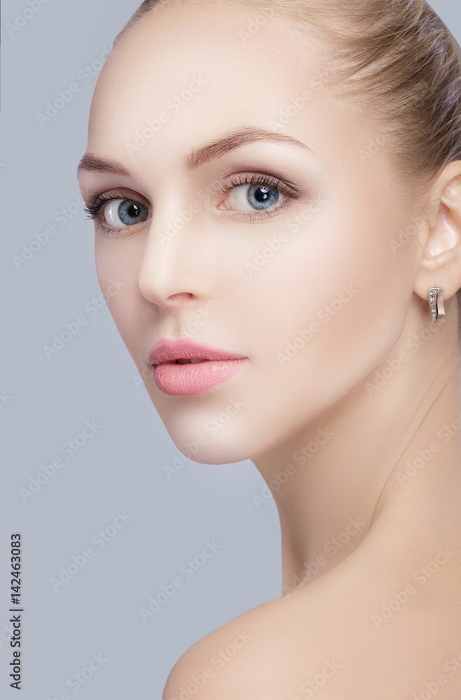 portrait of beautiful young blonde woman with blue eyes on grey background. girl with clean skin