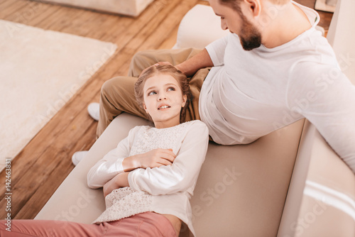 Adorable little girl with happy father together on sofa at home
