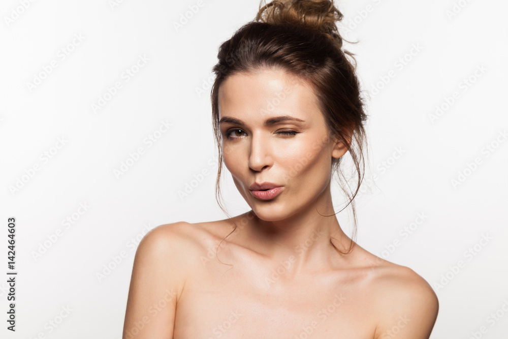 Happy brunette woman with naked shoulders sends an air kiss on a white background Happy brunette woman with naked shoulders sends an air kiss on a white background