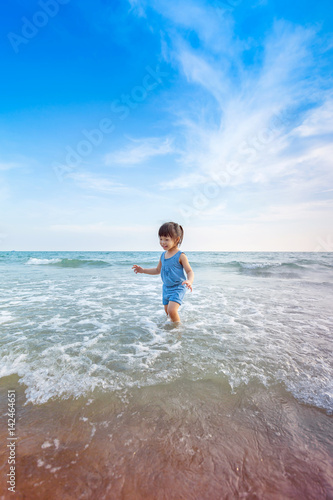 little girl playing on the beach in summer time sunset