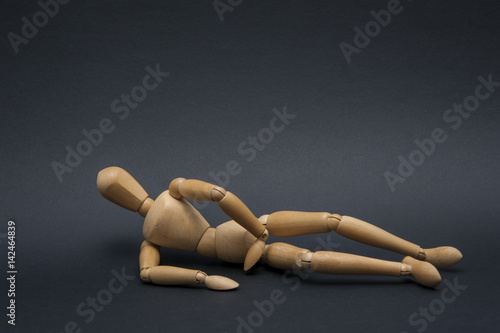 Person represented by a wooden dummy lied down and being asleep on the side with his hand below his head.
