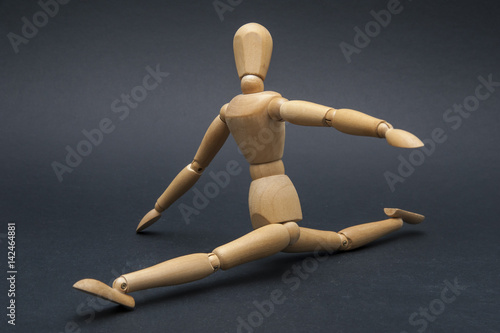 Person represented by a wooden dummy performing the splits and showing how flexible he is.