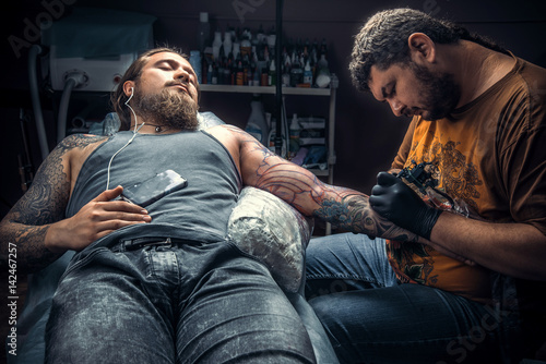 Tattoo specialist create tattoo in tattoo parlor