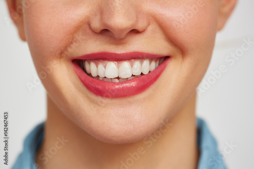 Close-up shot of female face with charming toothy smile against white background