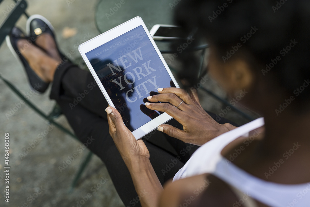 USA, New York City, woman sitting in a park using travel guide on tablet
