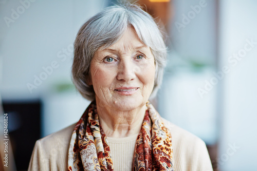 Foto Head and shoulders portrait of pensive elderly woman in beige sweater and colorf