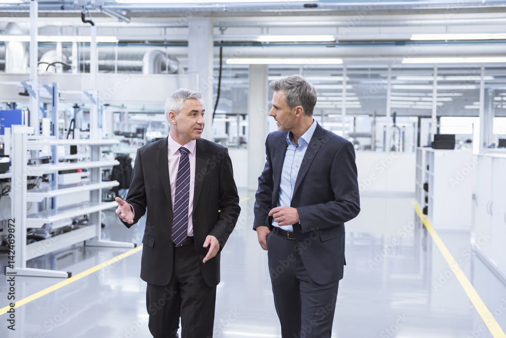 Two managers having a meeting at the shop floor of a factory Two managers having a meeting at the shop floor of a factory