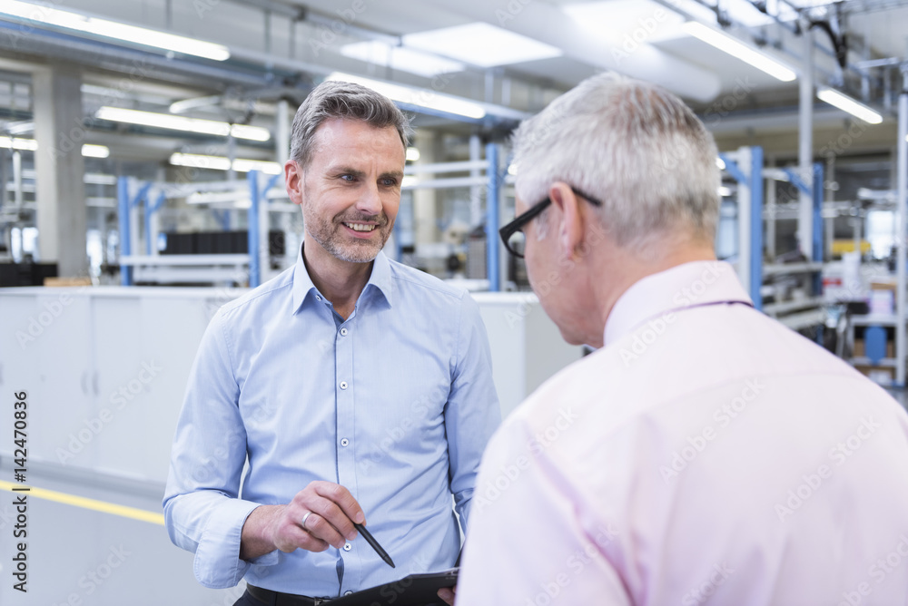 Two mangers discussing on shop floor of company Two mangers discussing on shop floor of company