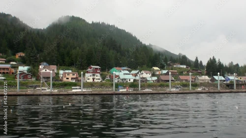 Wharf for boats on calm water of Pacific Ocean on background coast in Alaska. Amazing landscapes. Beautiful rest and tourism in a cool climate. Unique picture of nature in America. Wharf for boats on calm water of Pacific Ocean on background coast in Alaska. Amazing landscapes. Beautiful rest and tourism in a cool climate. Unique picture of nature in America.