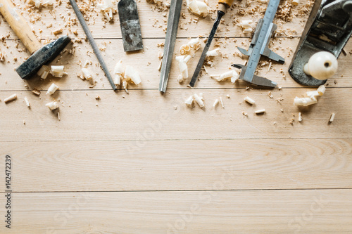 High angle view of shabby woodworking tools lying on wooden table, shavings scattered everywhere photo