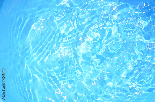 Blue pool water with sun reflections.Shining blue water ripple background.