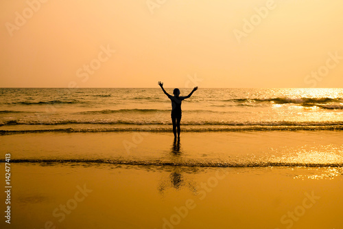 Silhouette of child holding his hands up on the beach © natchas