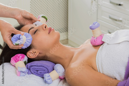 Woman has herbal ball massage in ayurveda spa wellness center