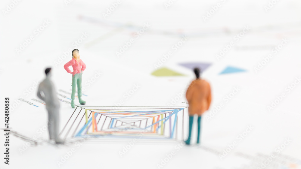 Miniature figures businessman standing on a graph chart Miniature figures businessman standing on a graph chart