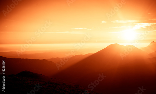 A beautiful, colorful, abstract mountain landscape with sun in a red tonality. Decorative, artistic look. © dachux21