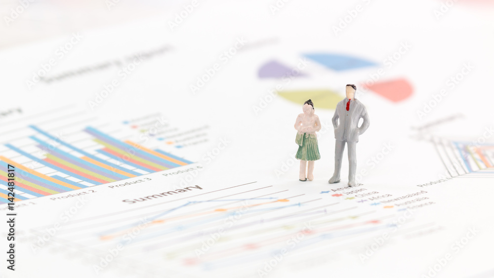 Miniature figures businessman standing on a graph chart Miniature figures businessman standing on a graph chart