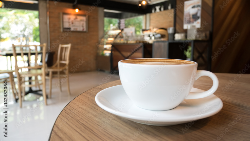 Fototapeta Kubek gorącej kawy latte cappuccino na drewnianym stole w kawiarni