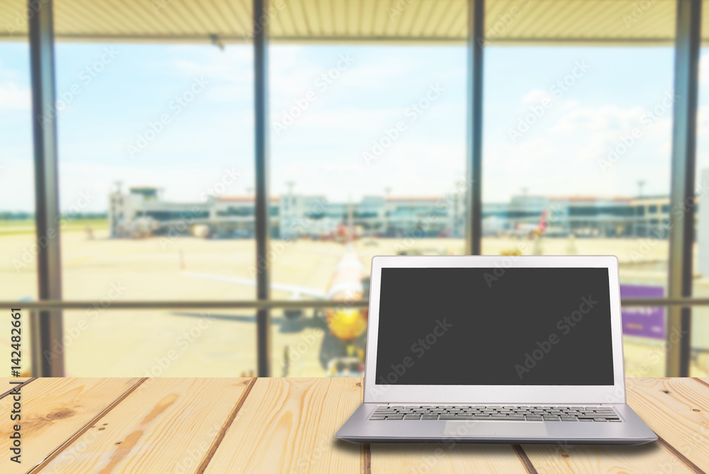 Laptop with blank screen on wooden table with airport at gate background, Laptop with blank screen on wooden table with airport at gate background,