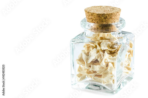 Dry crushed celery root in glass bottle isolated on white background. Closeup macro shot.