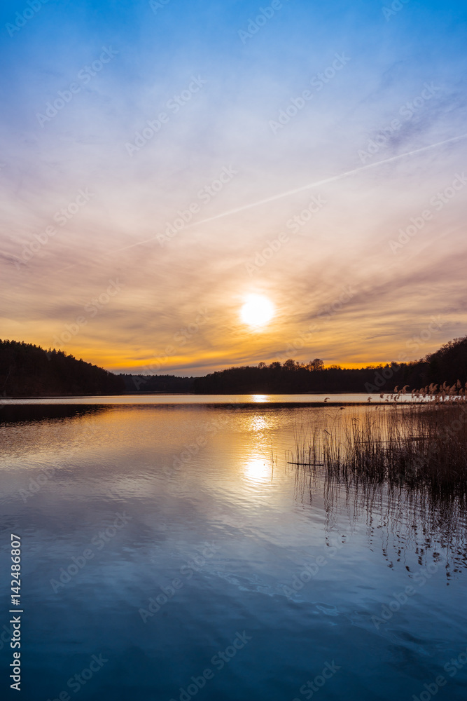 Setting sun over a tranquil lake with reeds