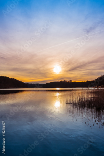 Setting sun over a tranquil lake with reeds