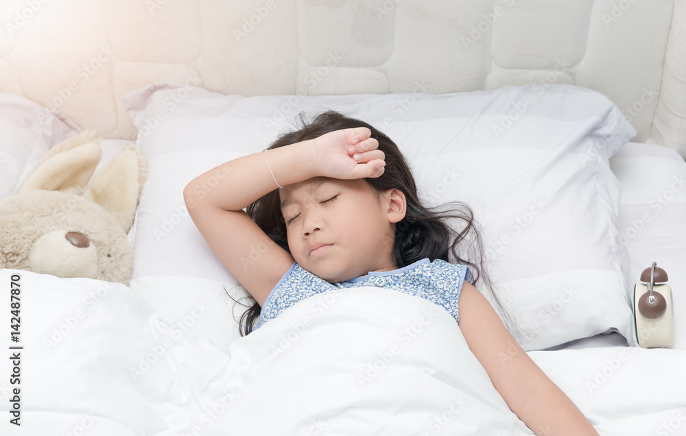 Child lying down suffering from a headache Child lying down suffering from a headache
