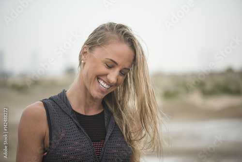 Strong athletic woman laughing with mud on her face after running or extreme sport with clean background © Paul