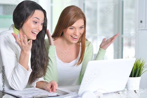 Two happy business woman using laptop