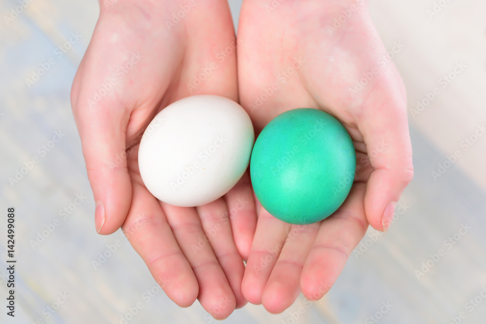 painted easter eggs white, green color in human hands
