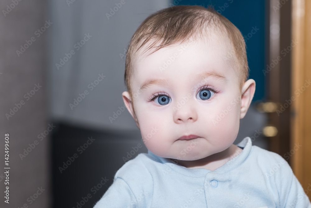 portrait of adorable little baby girl / boy with big blue eyes. kid looks into the camera with admiration