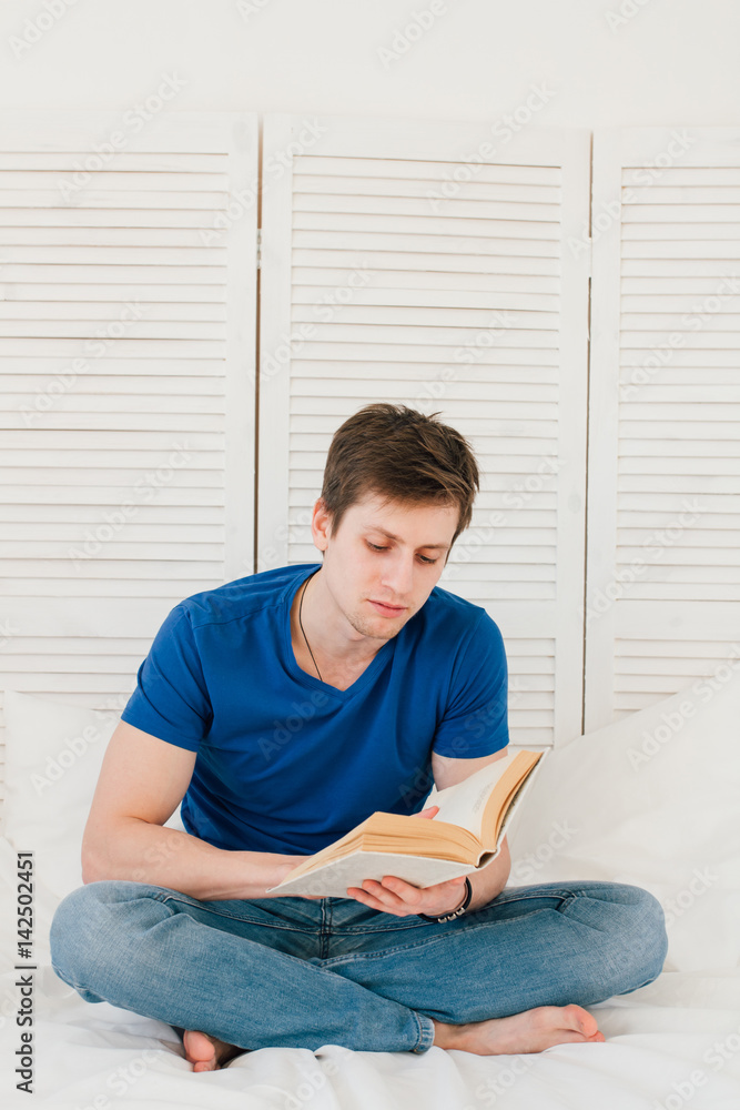 Man reading a book sitting on the bed Man reading a book sitting on the bed