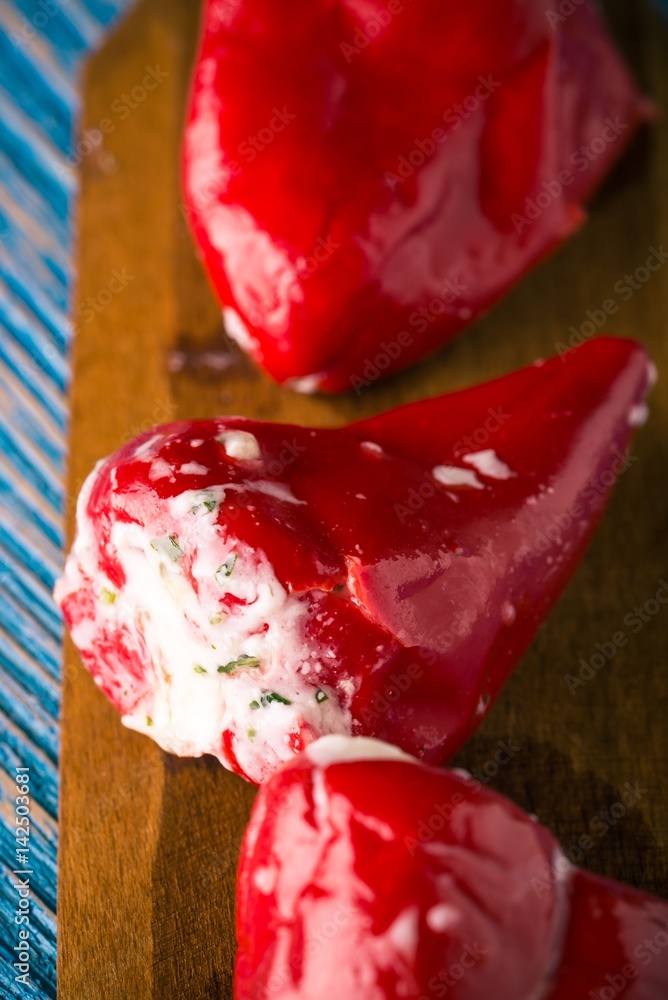 Three red chili pepper filled by cheese on wooden spoon Three red chili pepper filled by cheese on wooden spoon