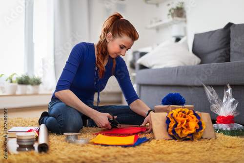 Smiling woman sitting on the floor decorating presents.