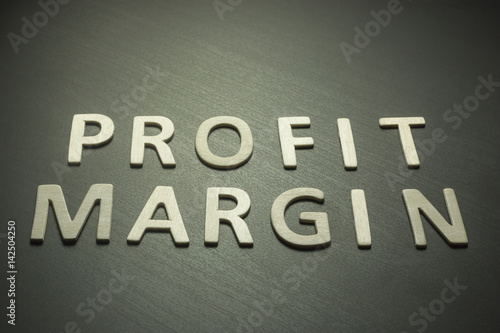 Profit margin written with wooden letters on a yellow background
