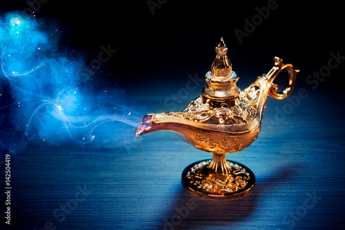 Magic Aladdin / Genie lamp with smoke on a dark background photo