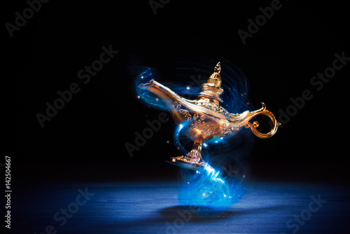 Magic Aladdin / Genie lamp floating on a dark background photo