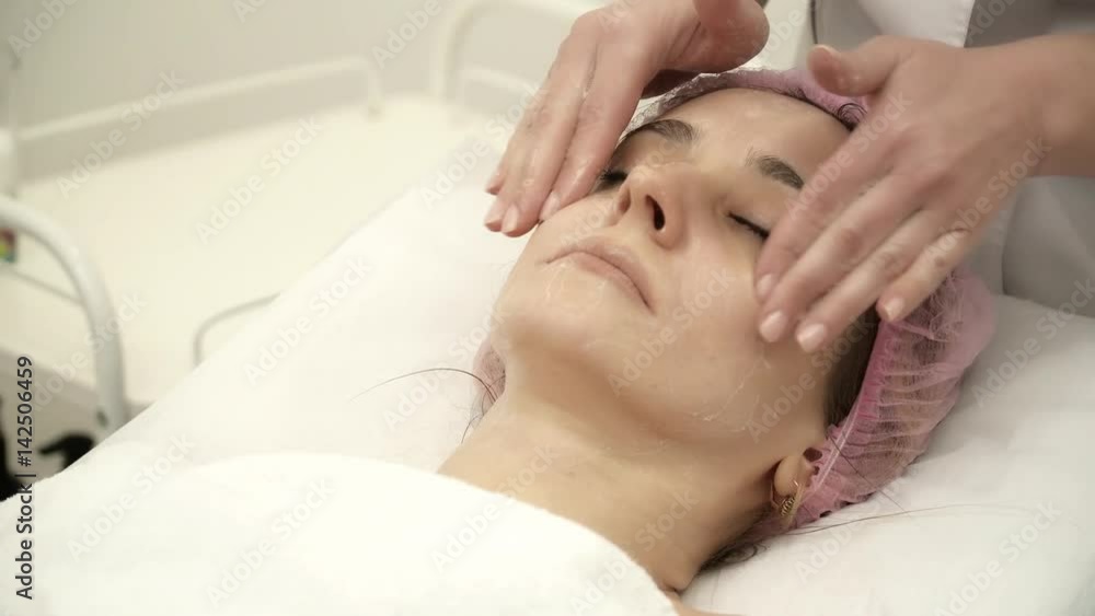 Beautician is making a facial rejuvenation procedure for a woman Beautician is making a facial rejuvenation procedure for a woman