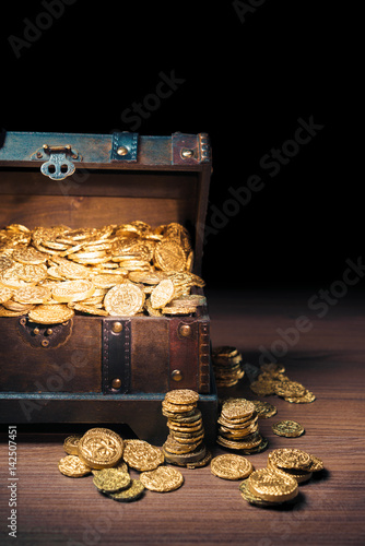 Open treasure chest with gold coins on a dark background