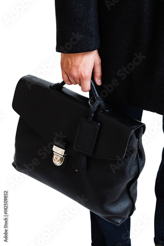 A man in a classic suit holds a black briefcase
