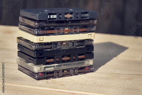 Filtered retro compact cassette audio magnetic tapes on wooden background