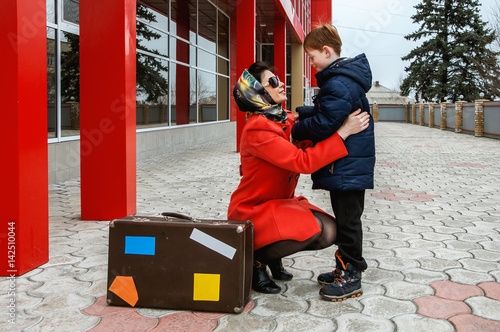 boy meets mom at the station. the girl in the red coat with suitcase. the meeting of mother and son