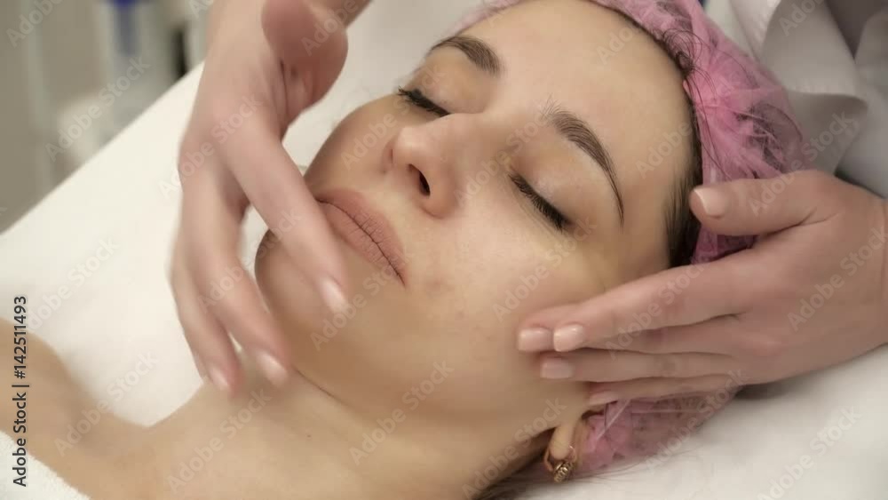 Beautician is making face massage for a woman in salon Beautician is making face massage for a woman in salon