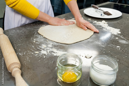 Cook, confectioner rolls out dough for pizza, pie, cake