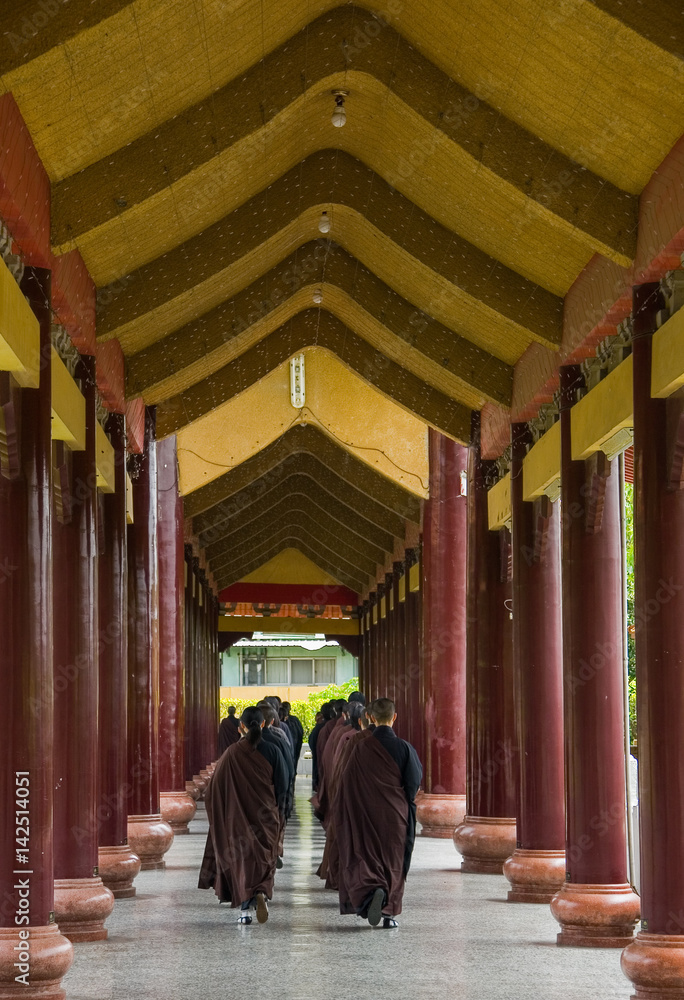 Monks on the way to prayer in a hallway with arched ceilings and columns